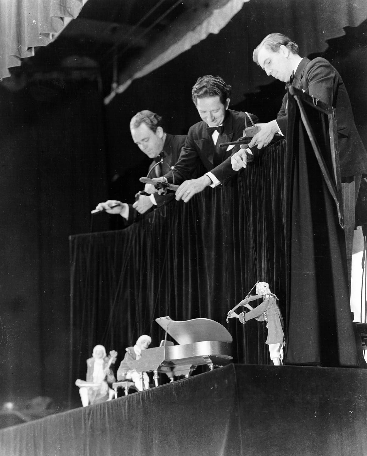 wearing tuxedos, the Yale Puppeteers hang the Haydn Trio puppets over a black curtain at the Barbizon Plaza
