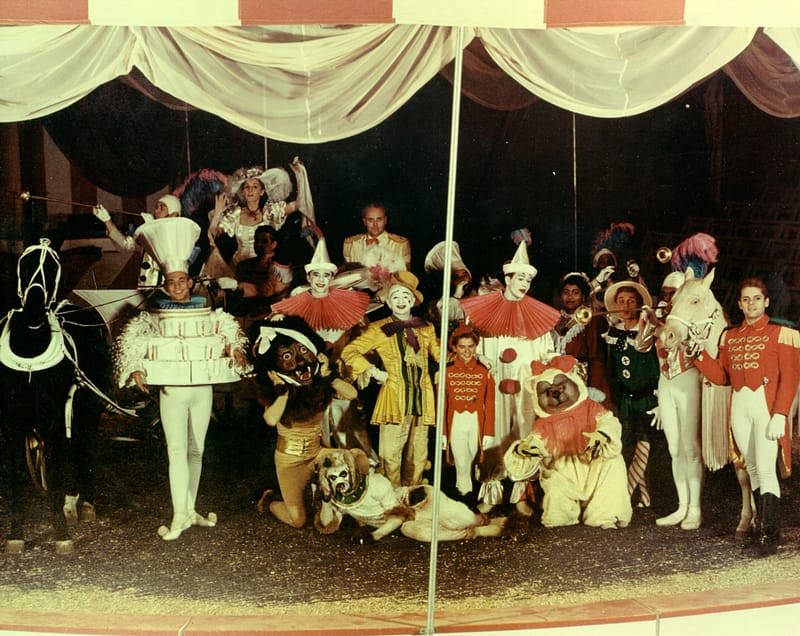 Cast of “Tommy Turnabout’s Circus,” A few horses and aproximatly 15 casts members in costume pose under a circus tent